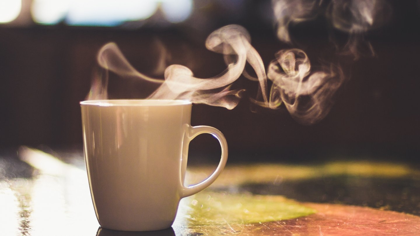 steaming cup of coffee on a wooden table