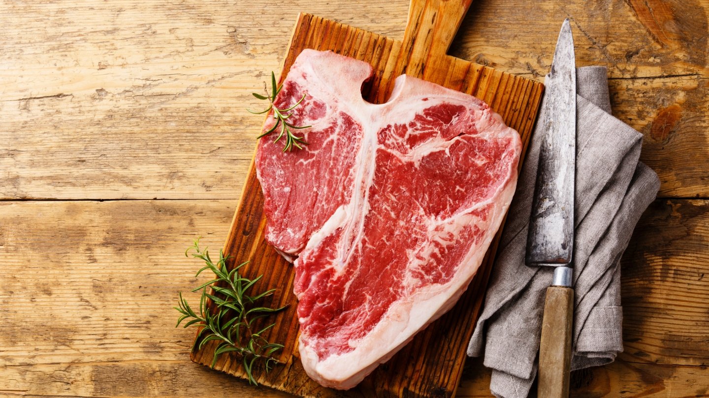 uncooked steak on a wood plank