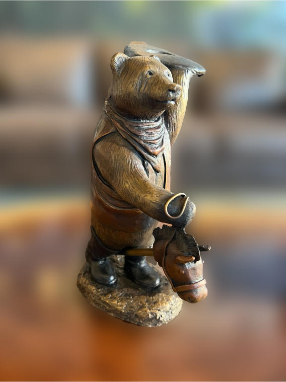 A small statue of a bear riding a wooden horse