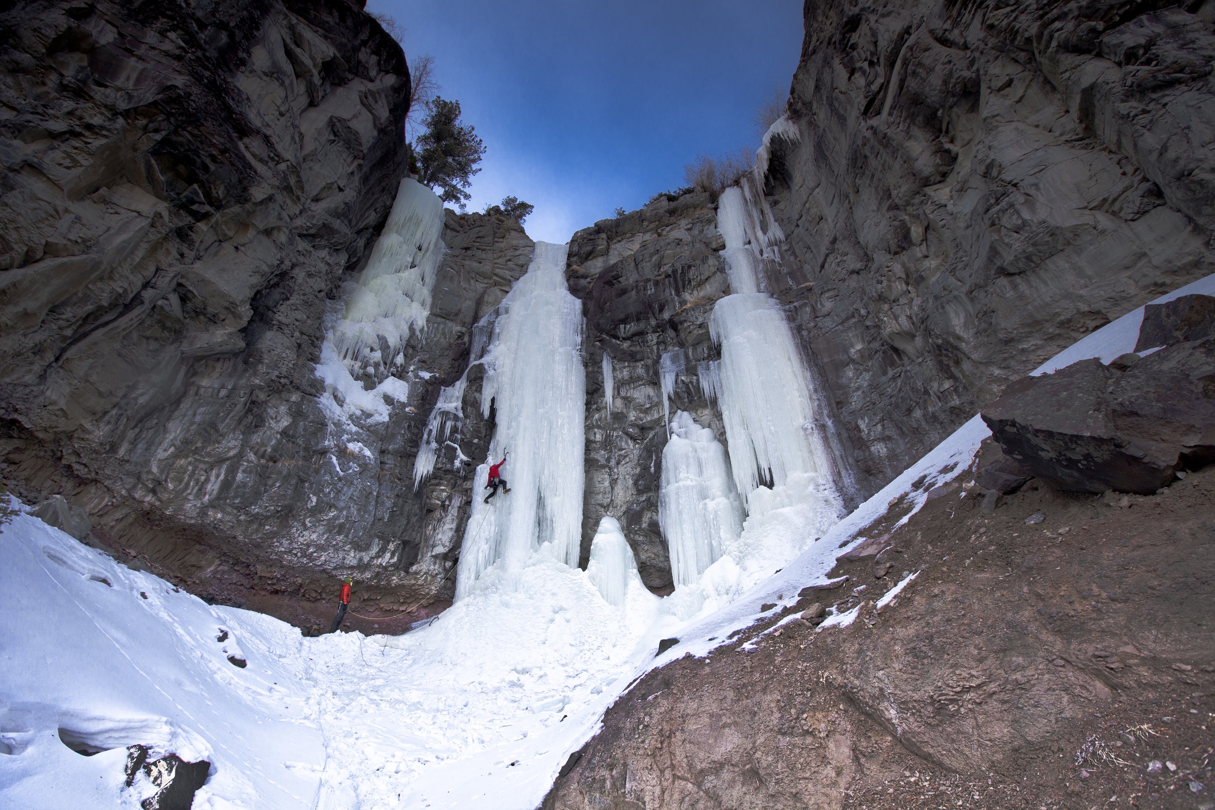 Two people in red jackets ice climbing