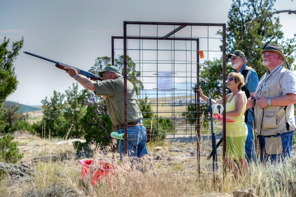 A man shooting a gun for sport while people watch