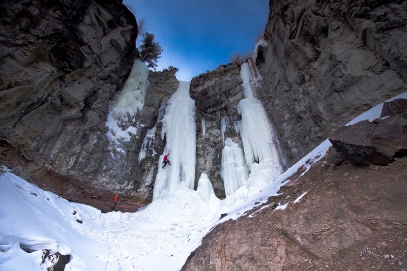 A person ice climbing on the side of a mountain