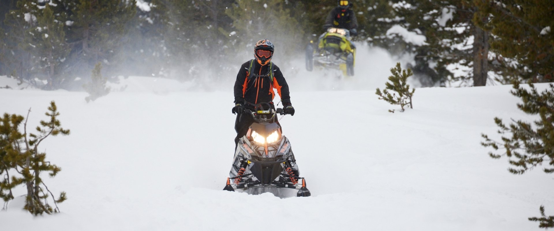 A person semi standing on a snowmobile