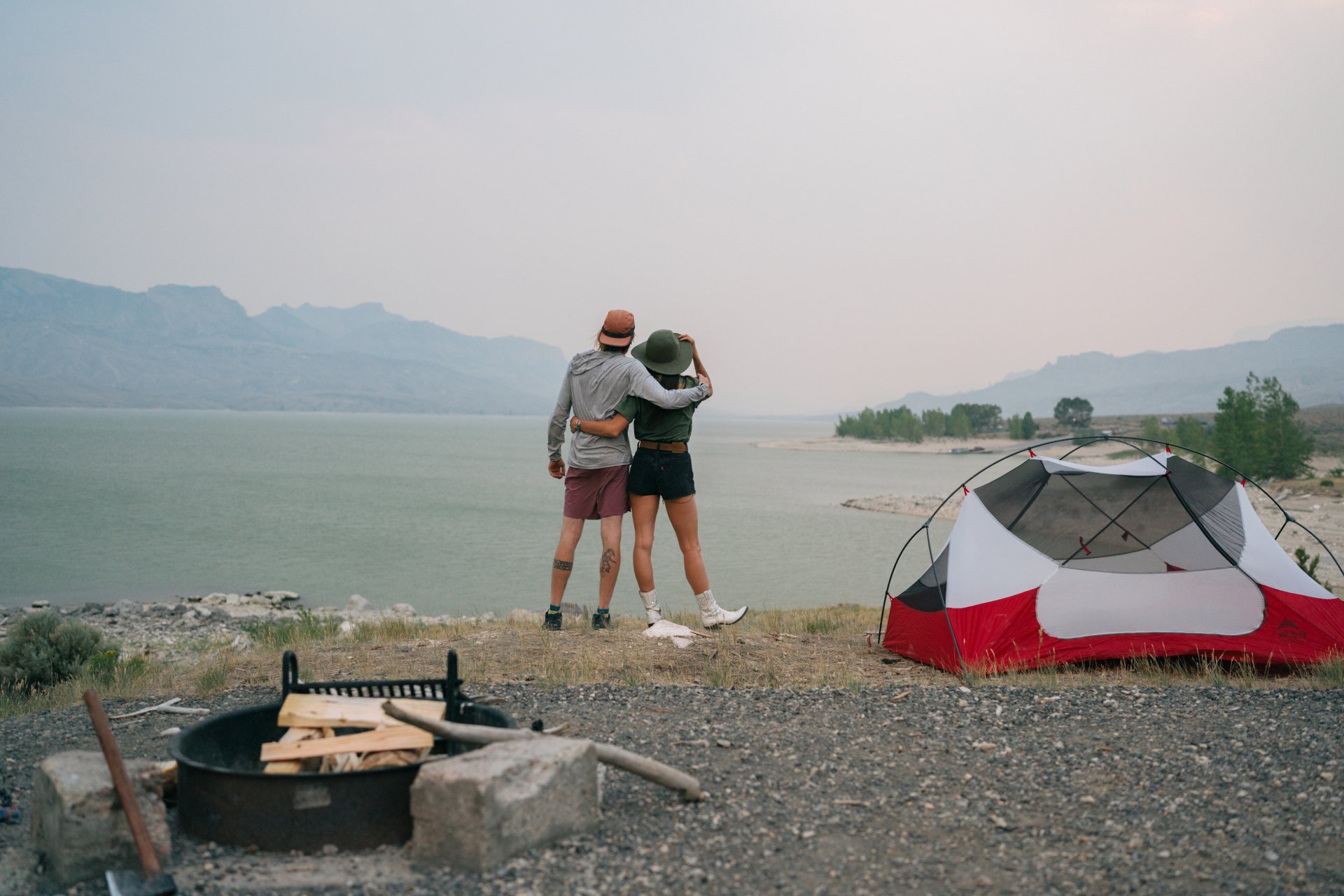 Two people standing looking out at the water beside their tent