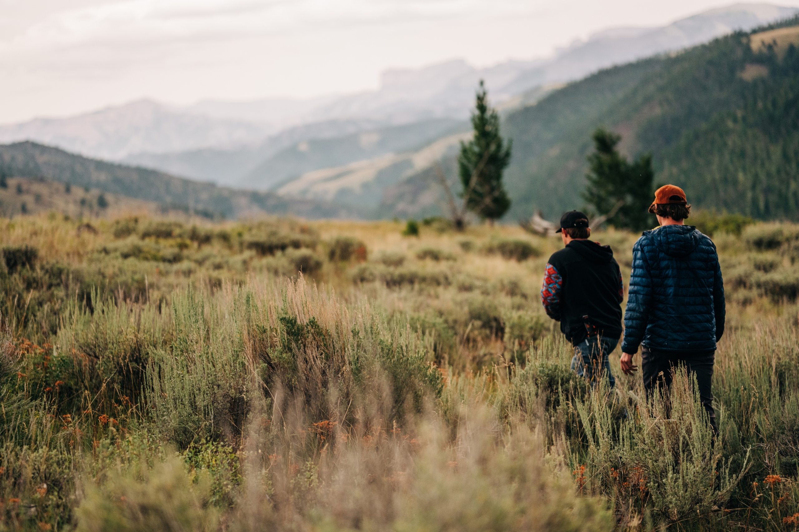 Two kids walking on a trail through the mountains