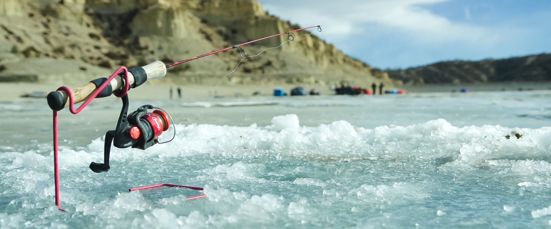 An up close image of a fishing rod in the ice on a lake