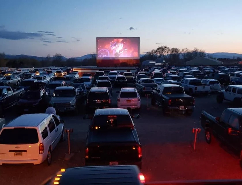 A large parking lot packed with cars, creating the perfect backdrop for an outdoor movie experience