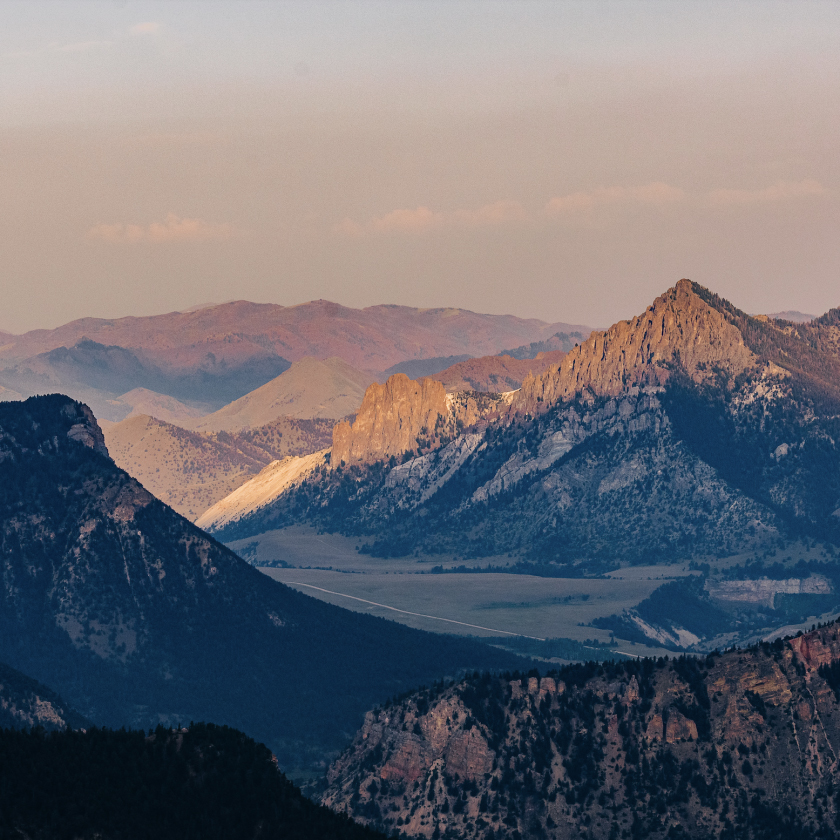 Scenic view of mountains and valleys bathed in warm hues during a stunning sunset.