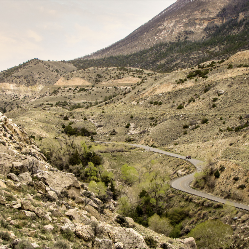 A majestic mountain stands tall beside a winding road, showcasing nature's beauty and adventure