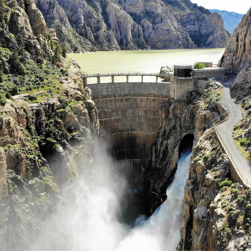 A large dam with water cascading out, creating a powerful flow and splashes below