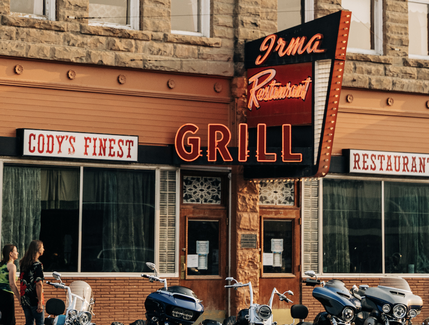 A charming restaurant with a bright sign, showcasing its name and inviting diners to come in and eat.