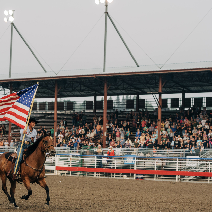 A large crowd watches a lady riding a horse as they run through the scene, creating an exciting atmosphere