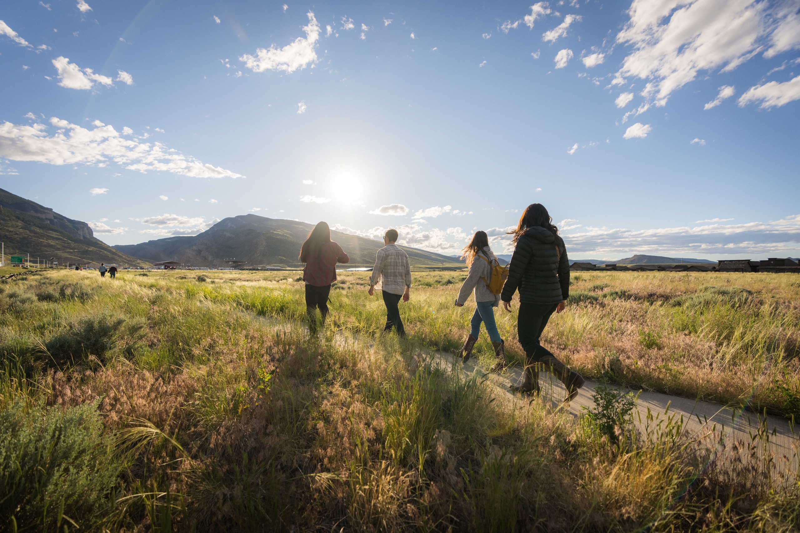 Four people walking on a path with the mountains in the background