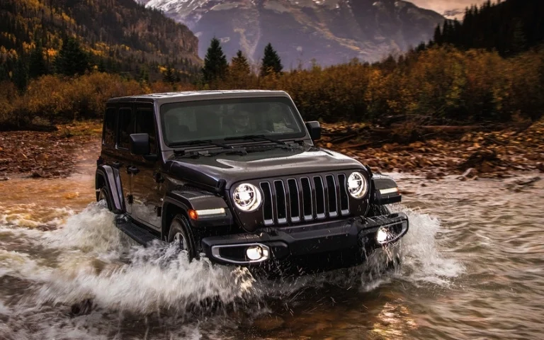 A jeep driving through a stream in the rockies