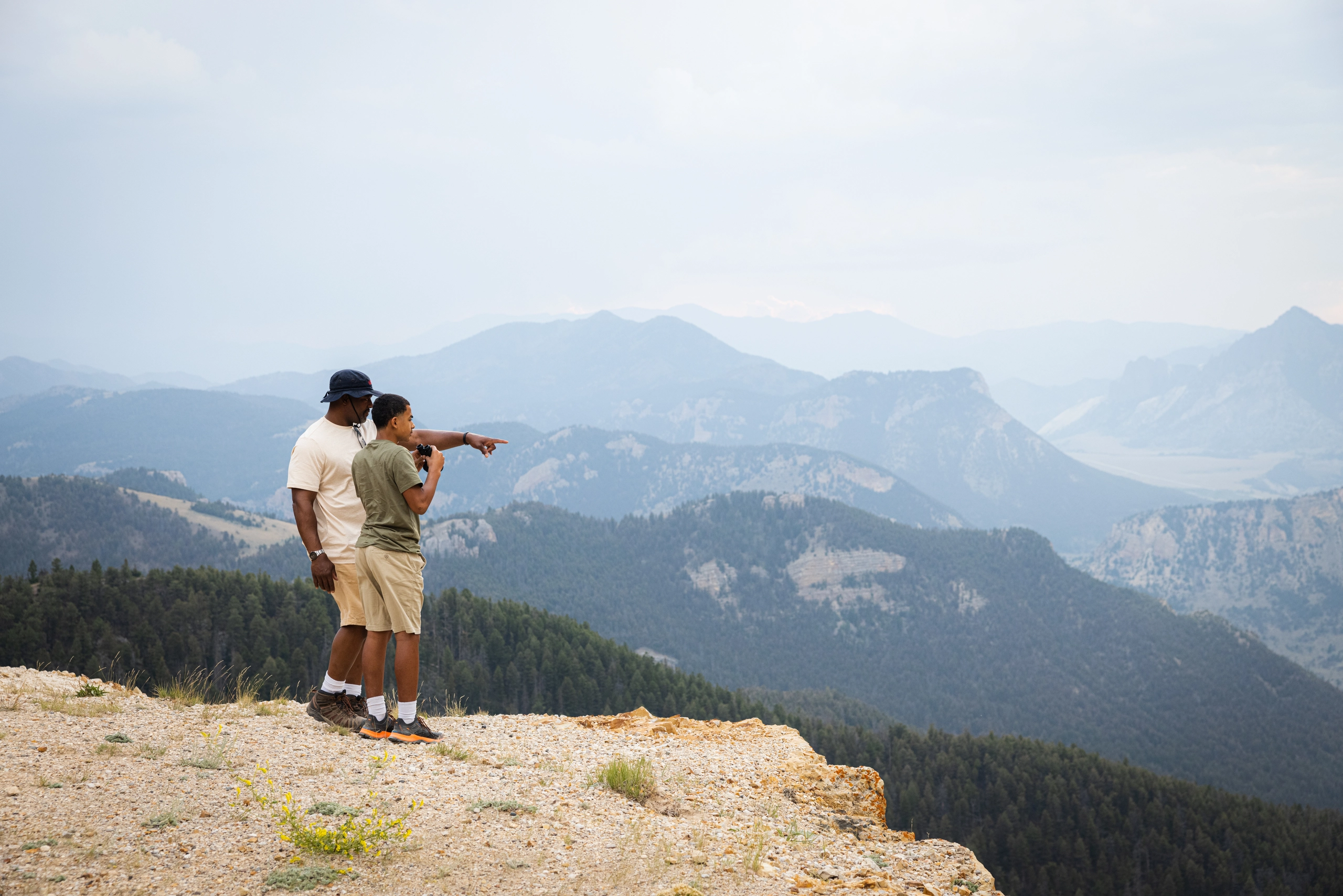 Two men looking off a cliff in the mountains