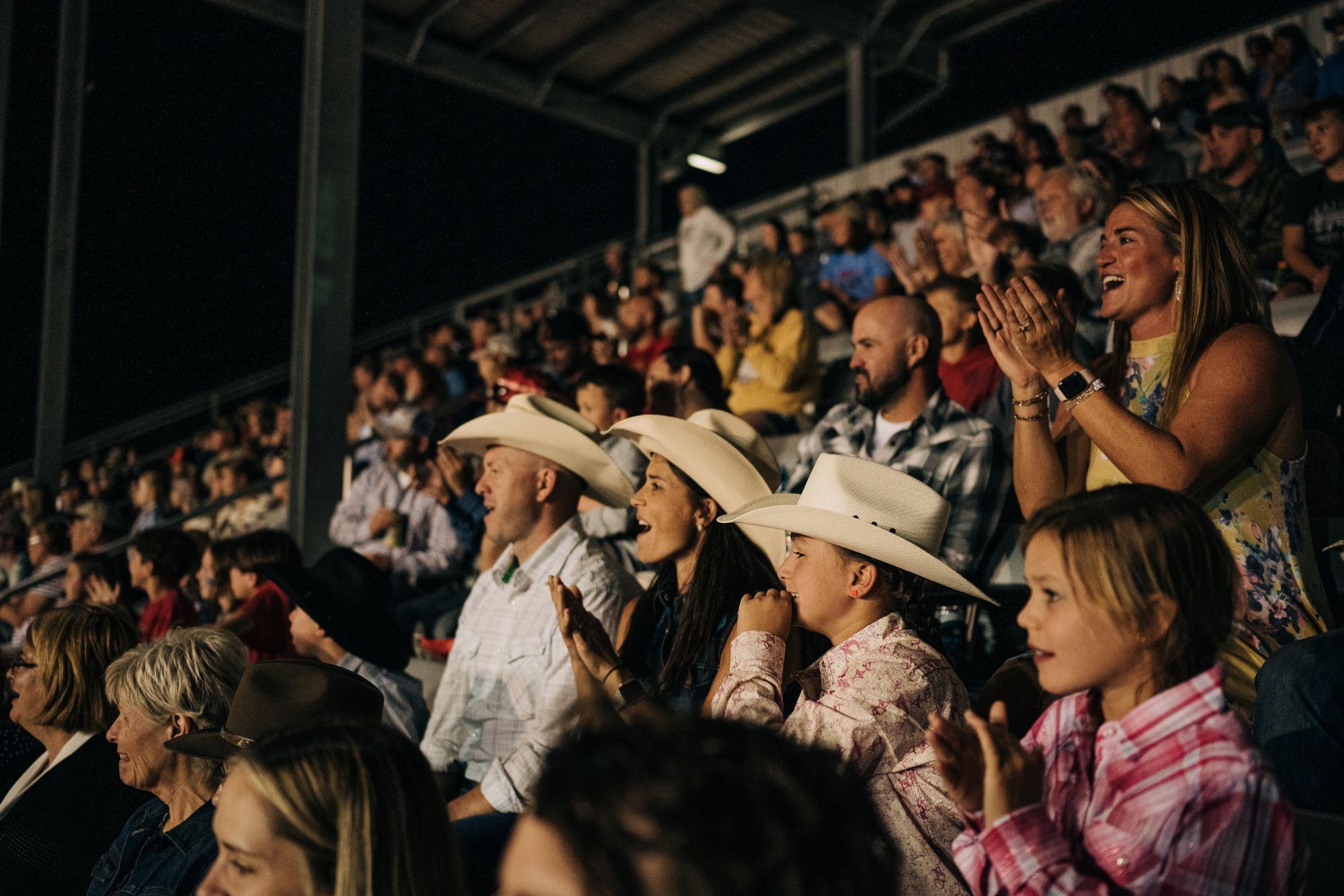 A group of people celebrating while in the stands at a rodeo