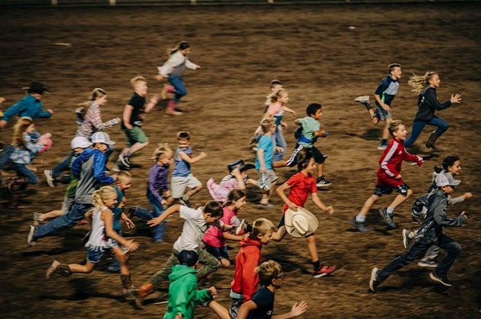 A bunch of kids running at the rodeo.