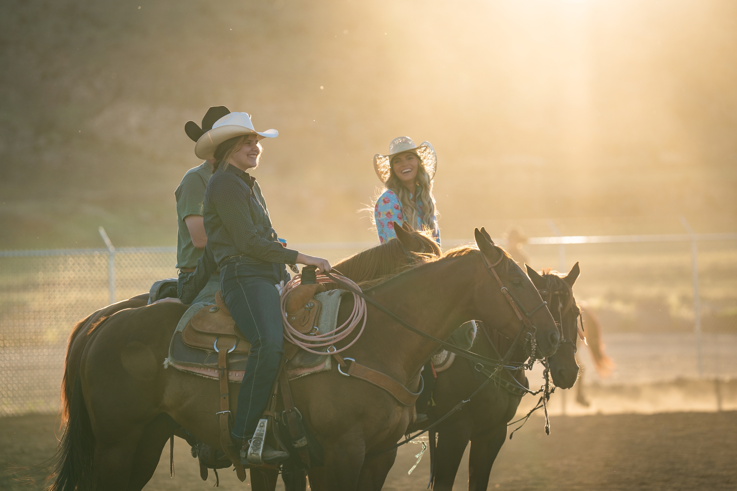 A man, woman and teenager on horses laughing