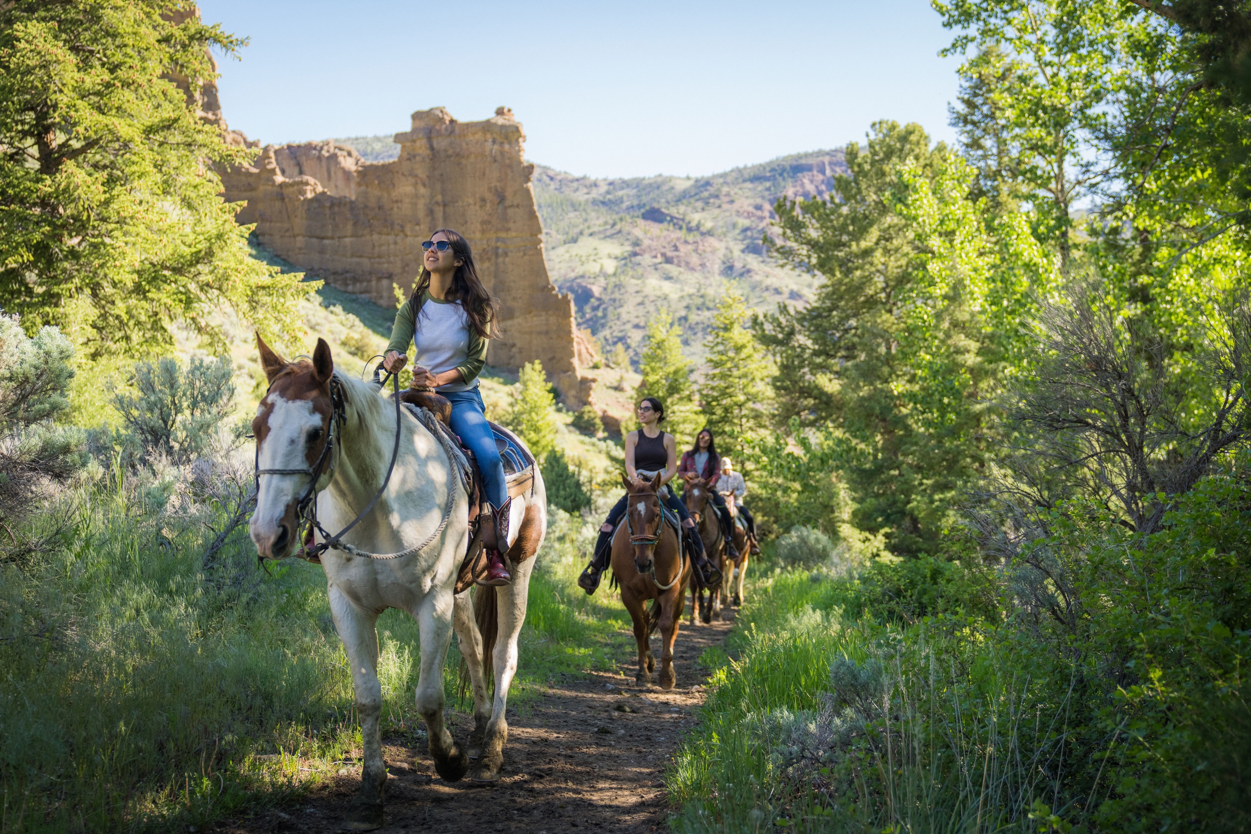 Four people horseback riding on a trail.