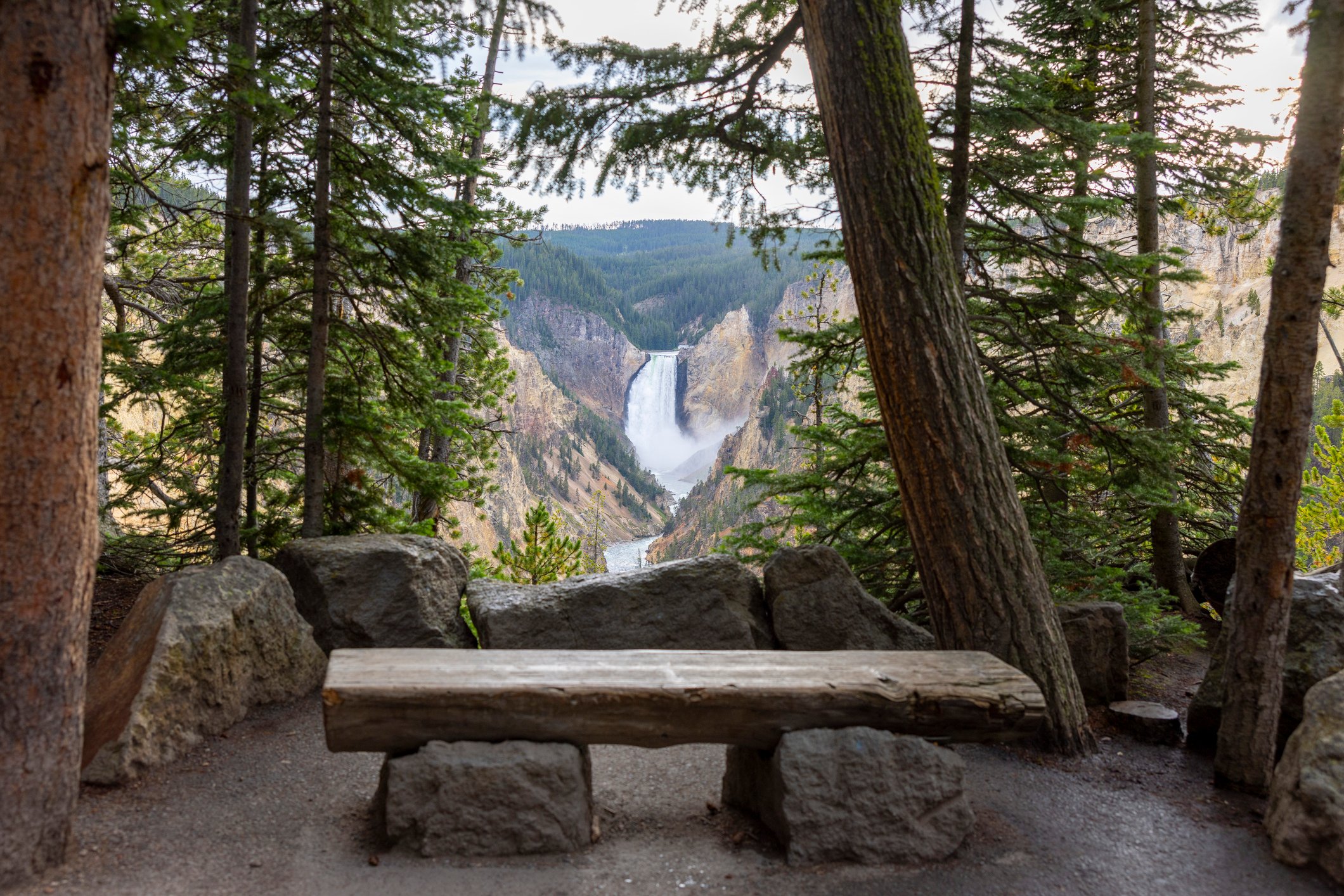 A wooden bench lookout where you can view a large waterfall from the mountains