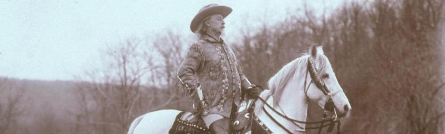 Buffalo Bill Cody in a hat rides a beautiful white horse, showcasing a classic Western scene