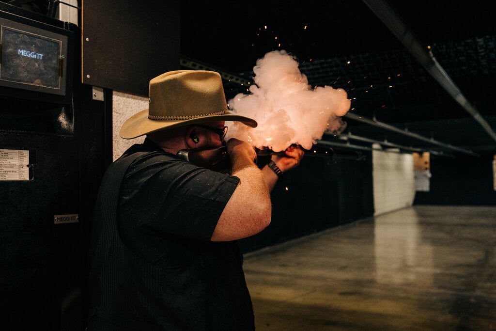 A man in a cowboy hat aims a gun, ready to shoot