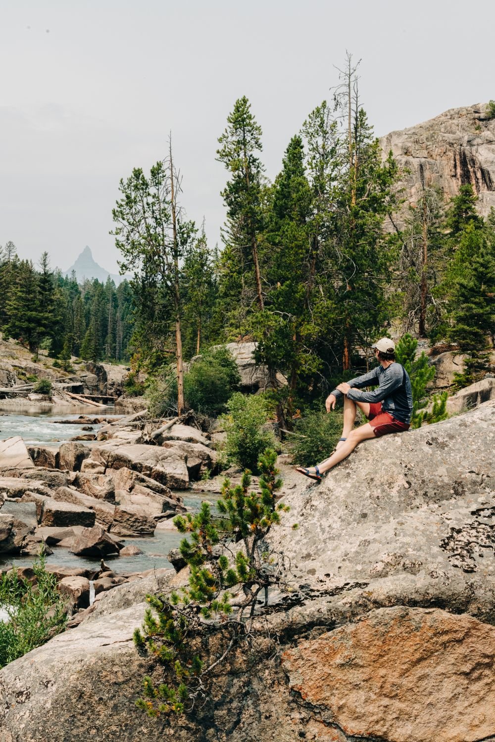 A man sitting on some rocks by a river