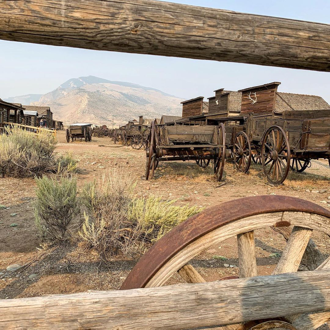 A vintage wooden wagon is parked beside a fence, adding a touch of nostalgia to the scenic outdoor setting