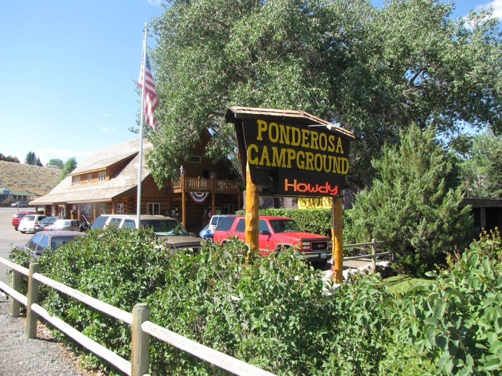 Parking cars near wooden house at Ponderosa campground under trees in Cody Yellowstone