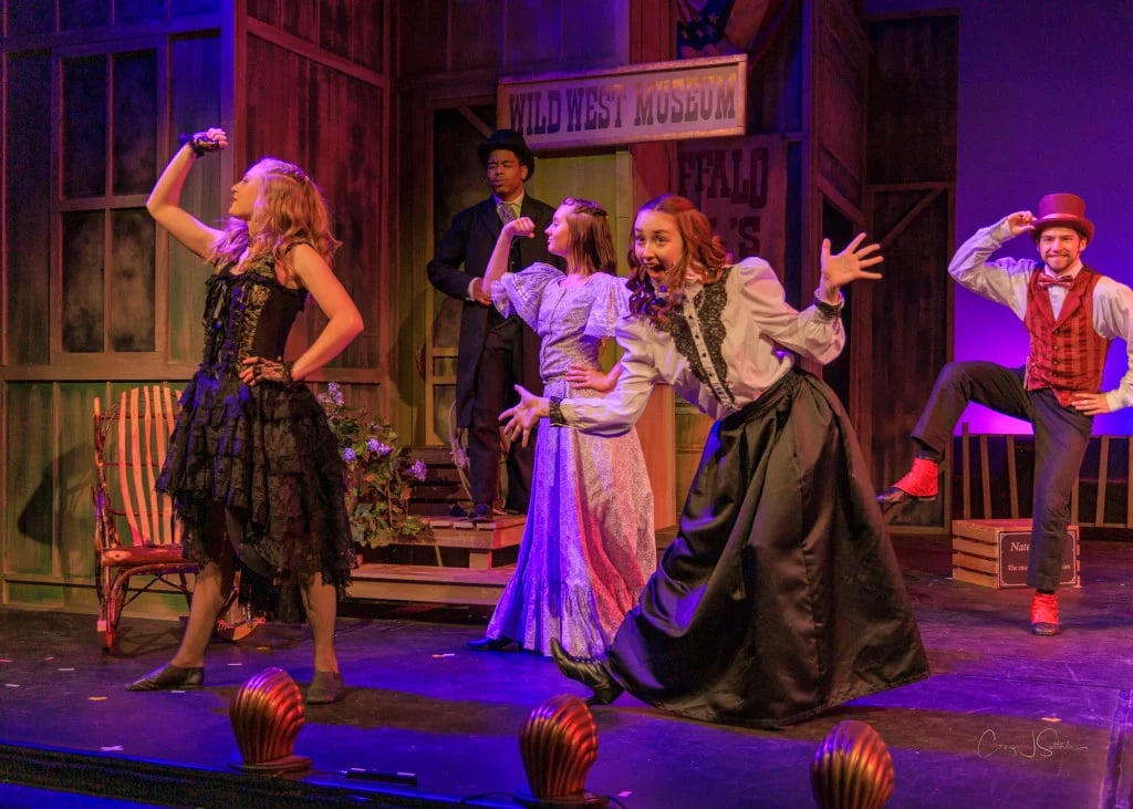 A dynamic ensemble of performers engaging the audience on stage during a theatrical production