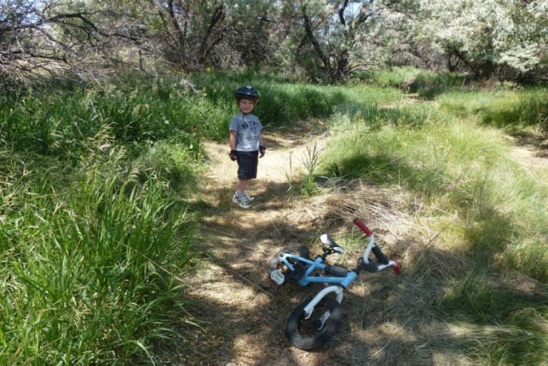 A child standing in front of his bike on a path at Yellowstone