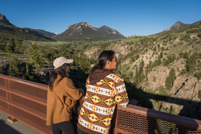 Two women looking out at the mountains from a bridge