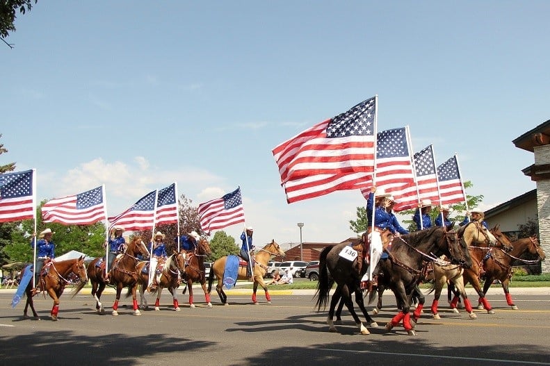 Ten people on horses with giant American flags.