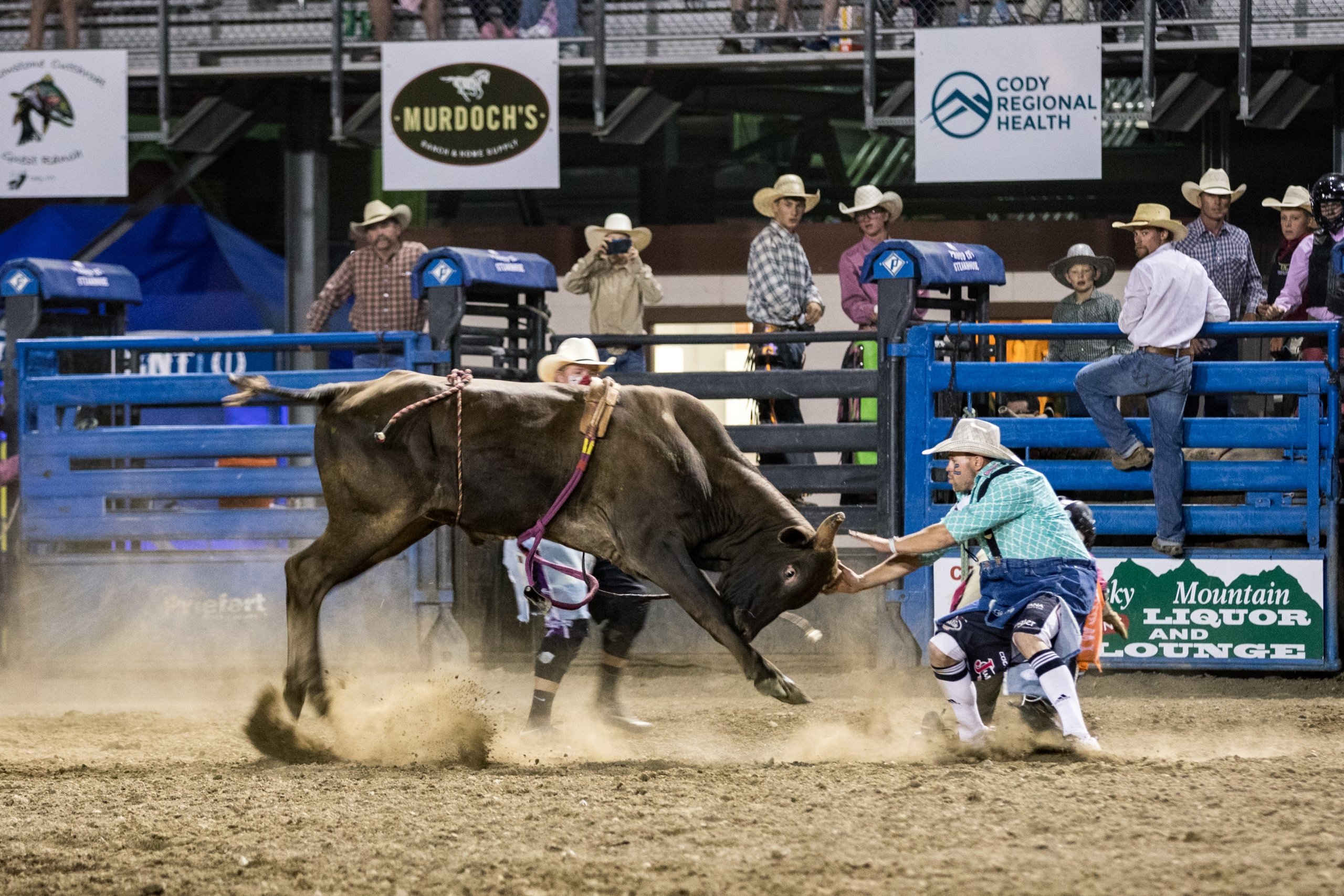 A man touching bull horns while at the rodeo