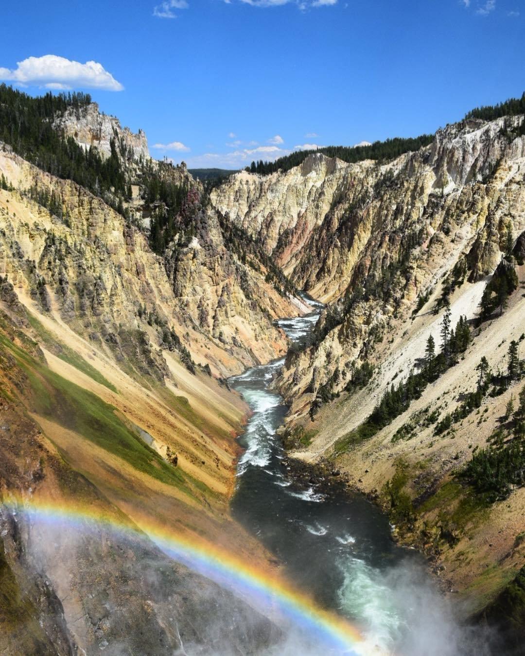 A river running through the mountains with a rainbow