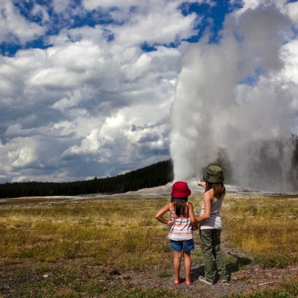 Two children looking at a some steam coming form the ground