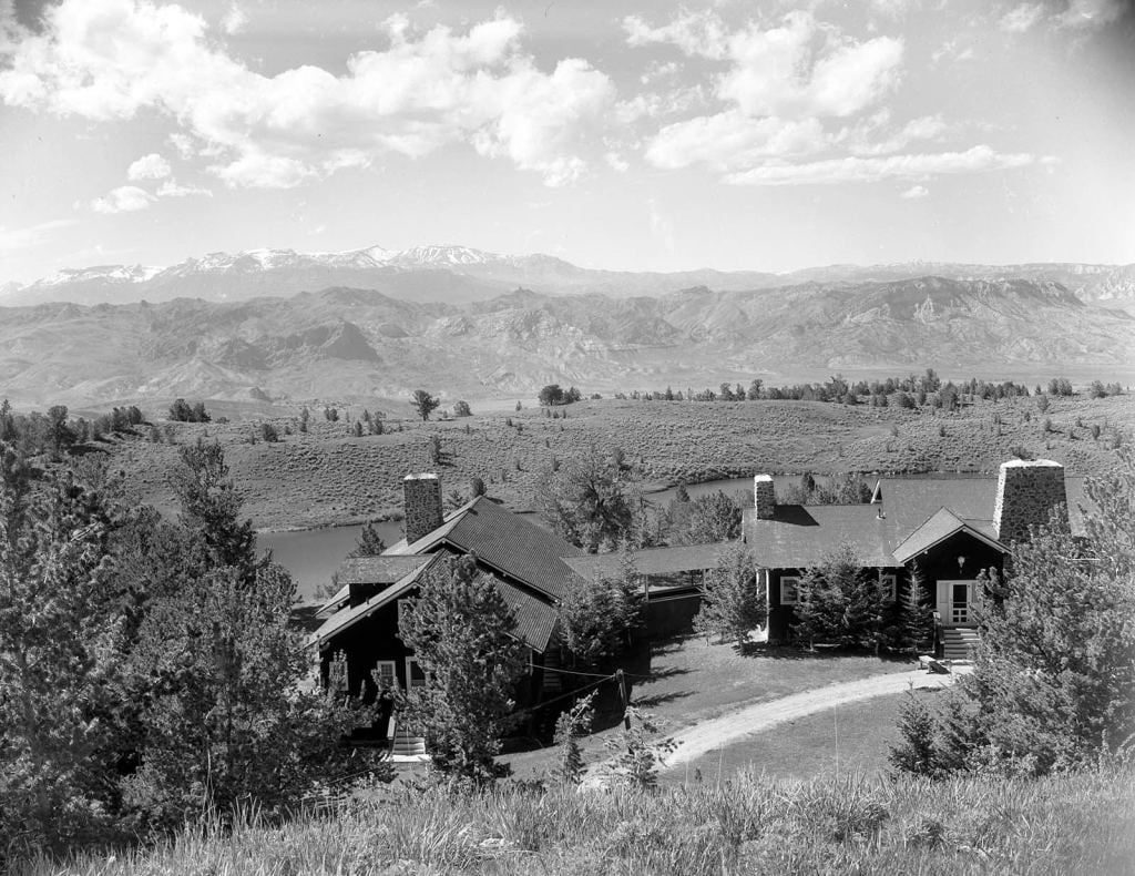 A black and white photo of a house in the mountains